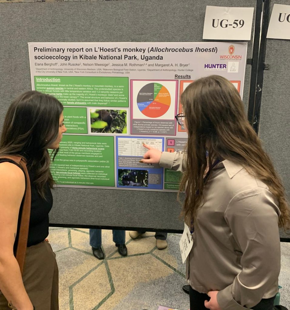 Two white women with brown hair looking at a scientific poster